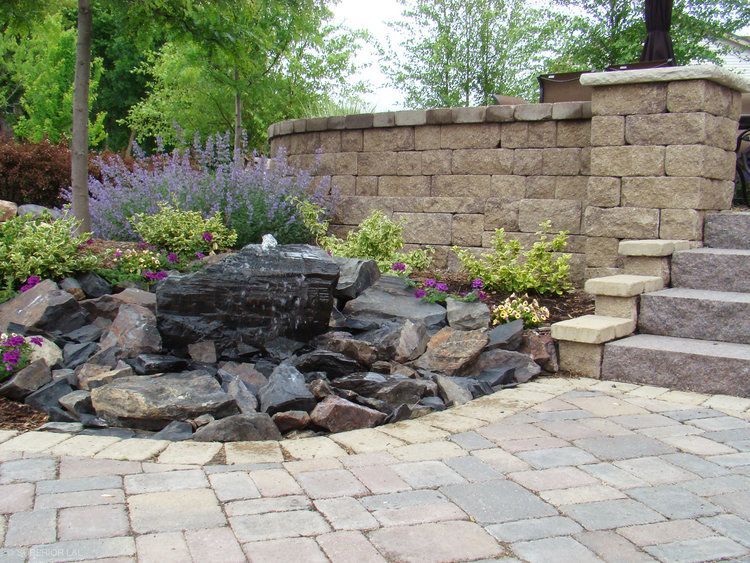 A stone wall with stairs and a fountain in the middle