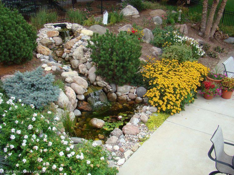 A garden with flowers and rocks and a pond