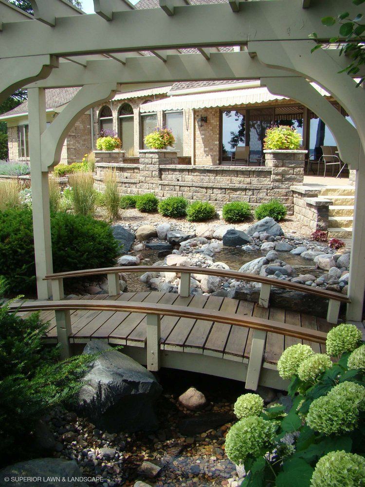 A wooden bridge over a stream in front of a house