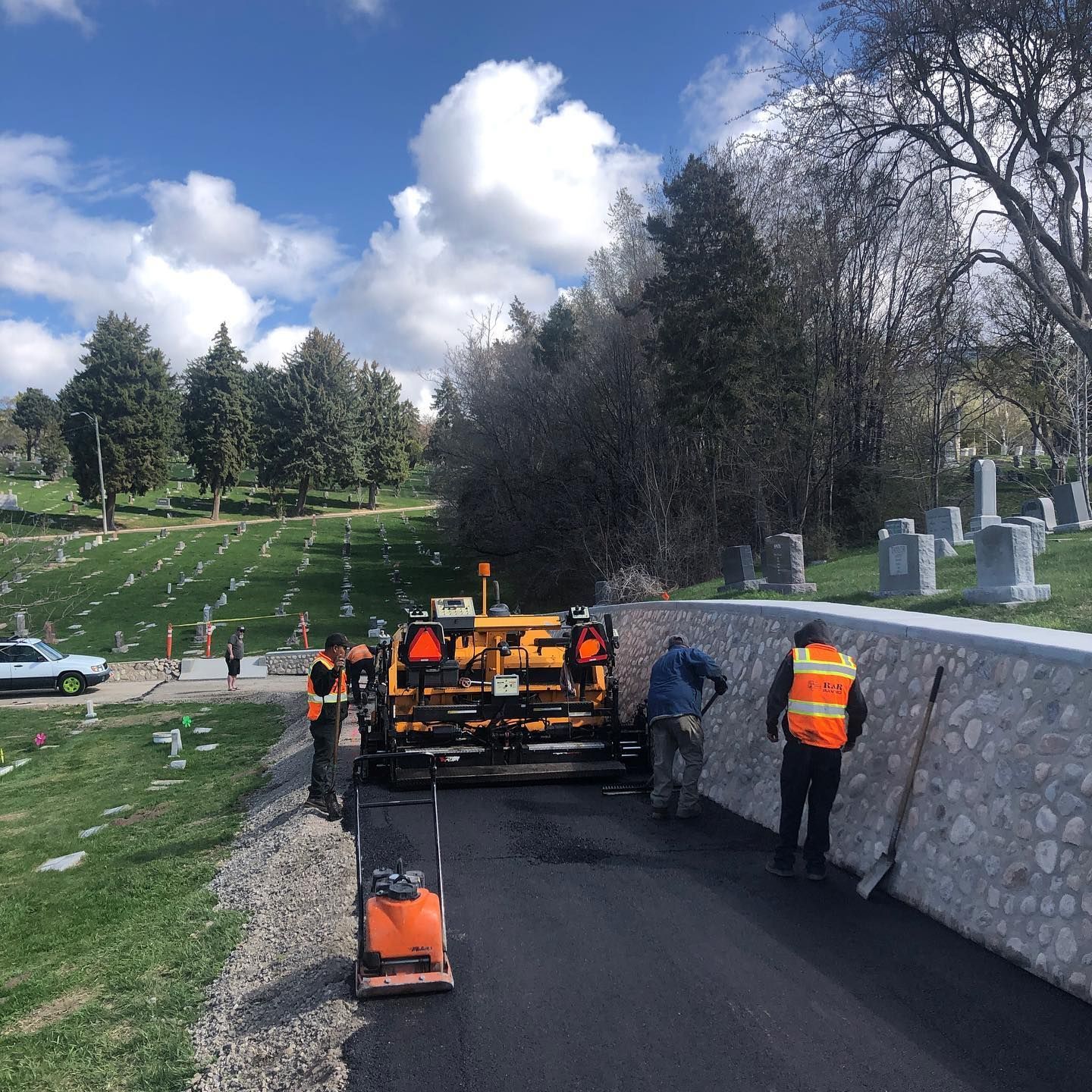 a group of construction workers are working on a road near a cemetery