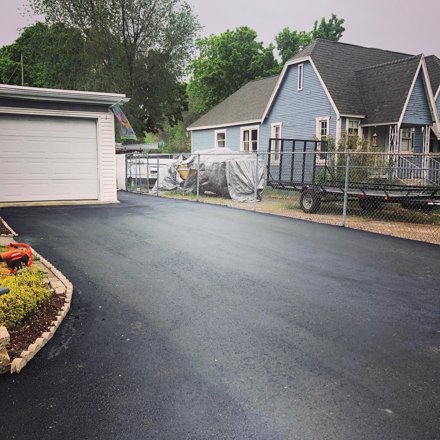 a driveway with a garage and a house in the background