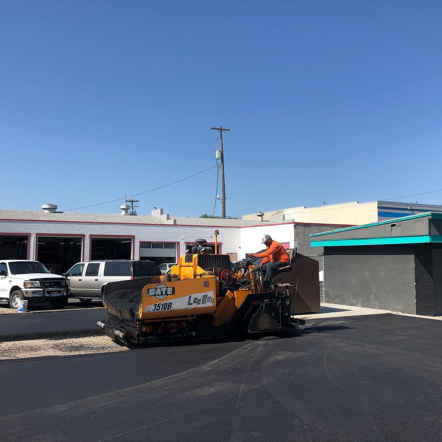 a man is sitting on top of a yellow asphalt paving machine .