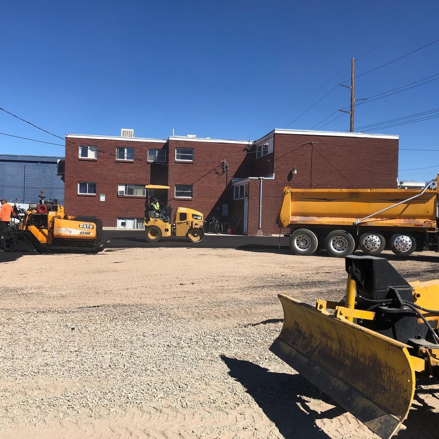a yellow dump truck is parked in front of a brick building