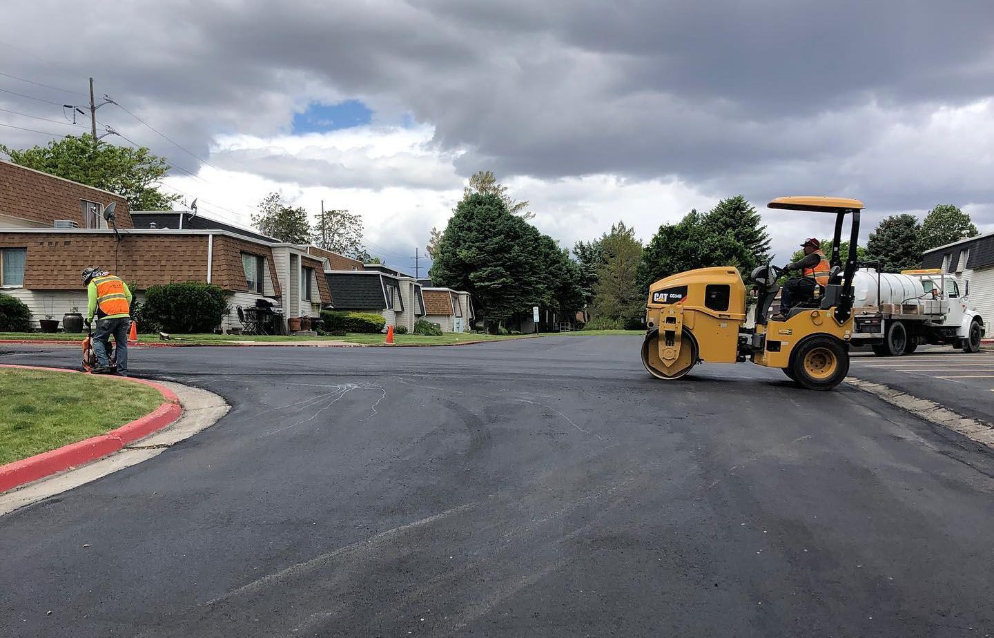 a yellow roller is rolling asphalt on a street