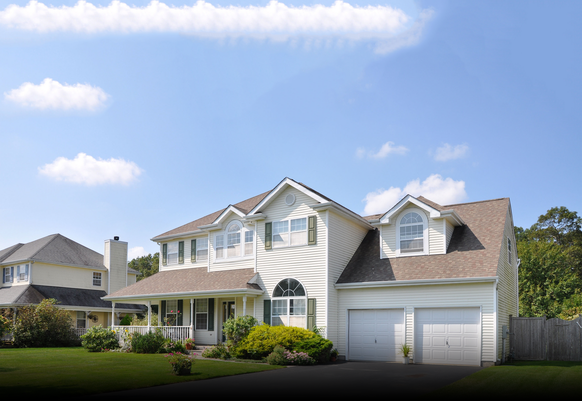 A white house with a brown roof and two garage doors