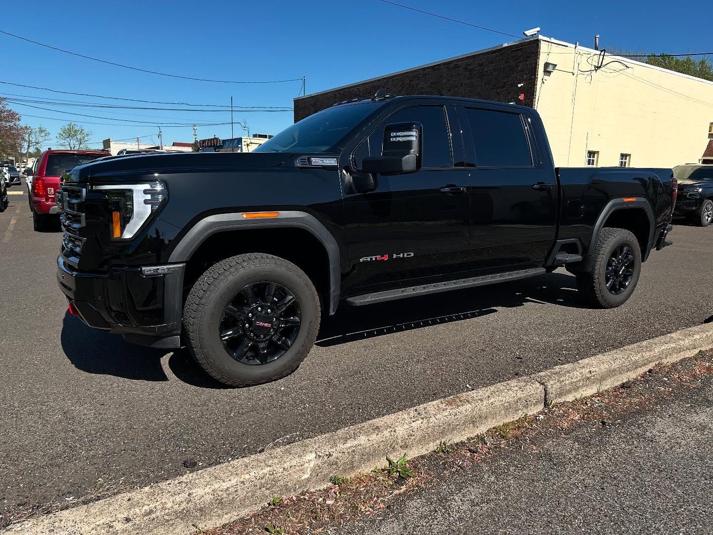 Black GMC truck parked in a lot, sunny day.