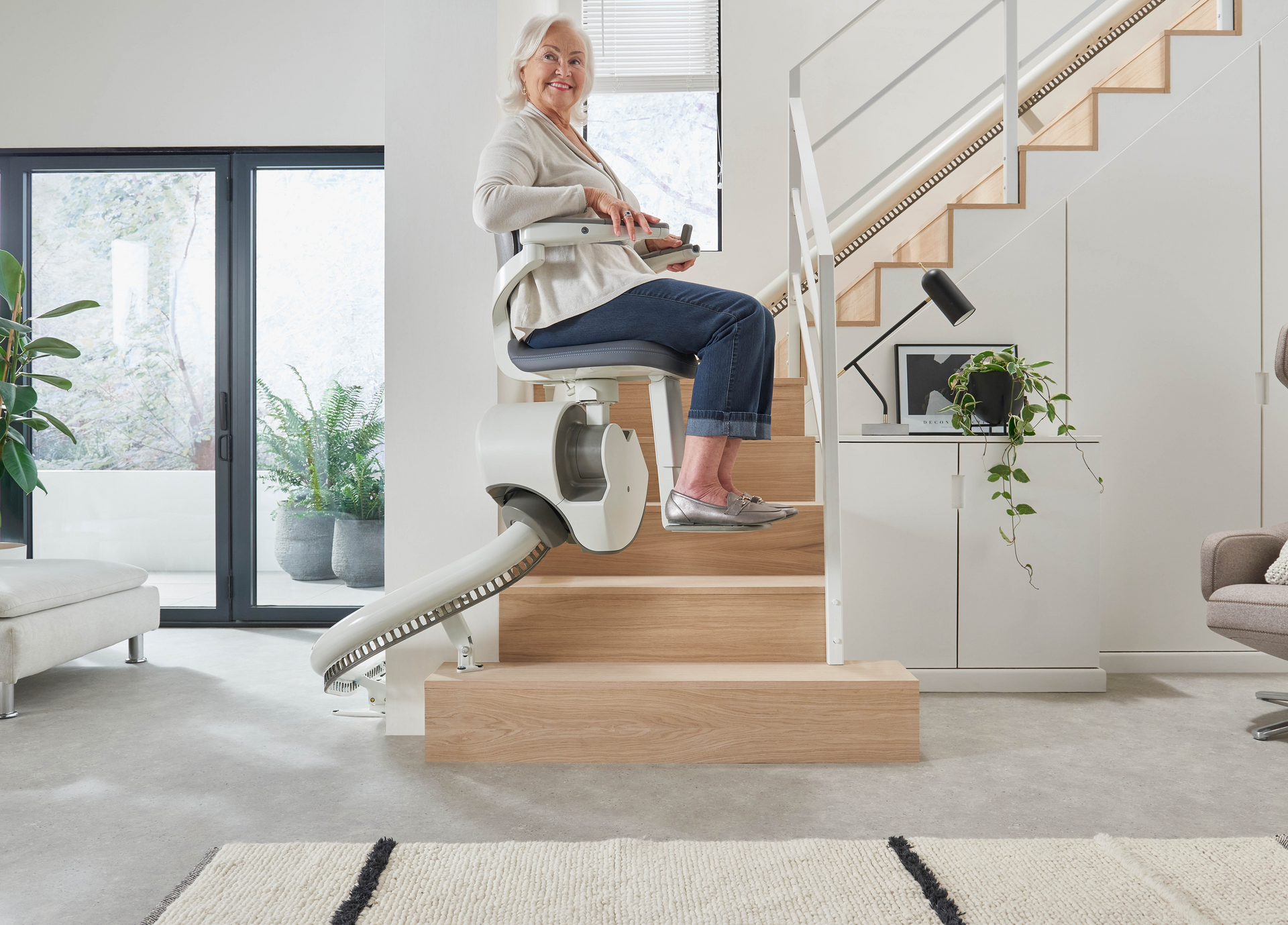 Person using a stairlift on a wooden staircase in a bright home interior