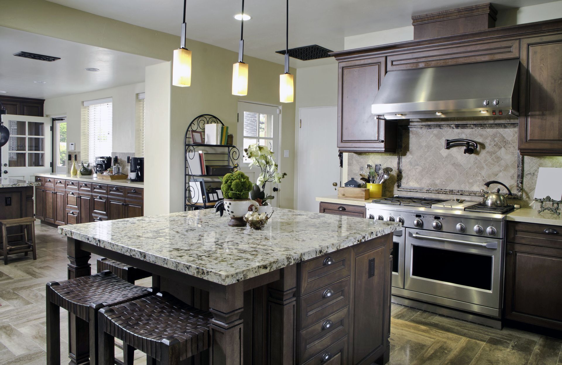 Modern kitchen with granite island, pendant lights, and stainless steel range and hood