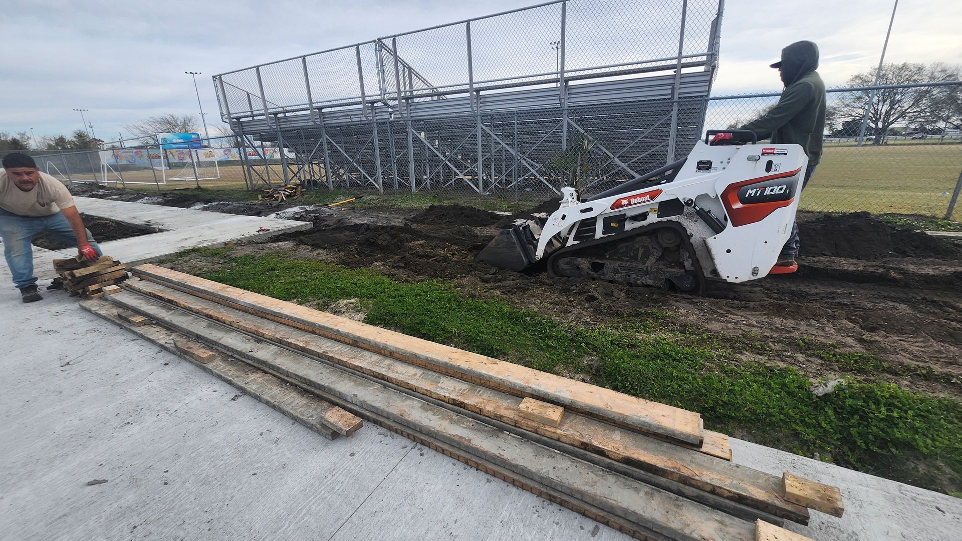 A man is driving a bulldozer next to a pile of wood.