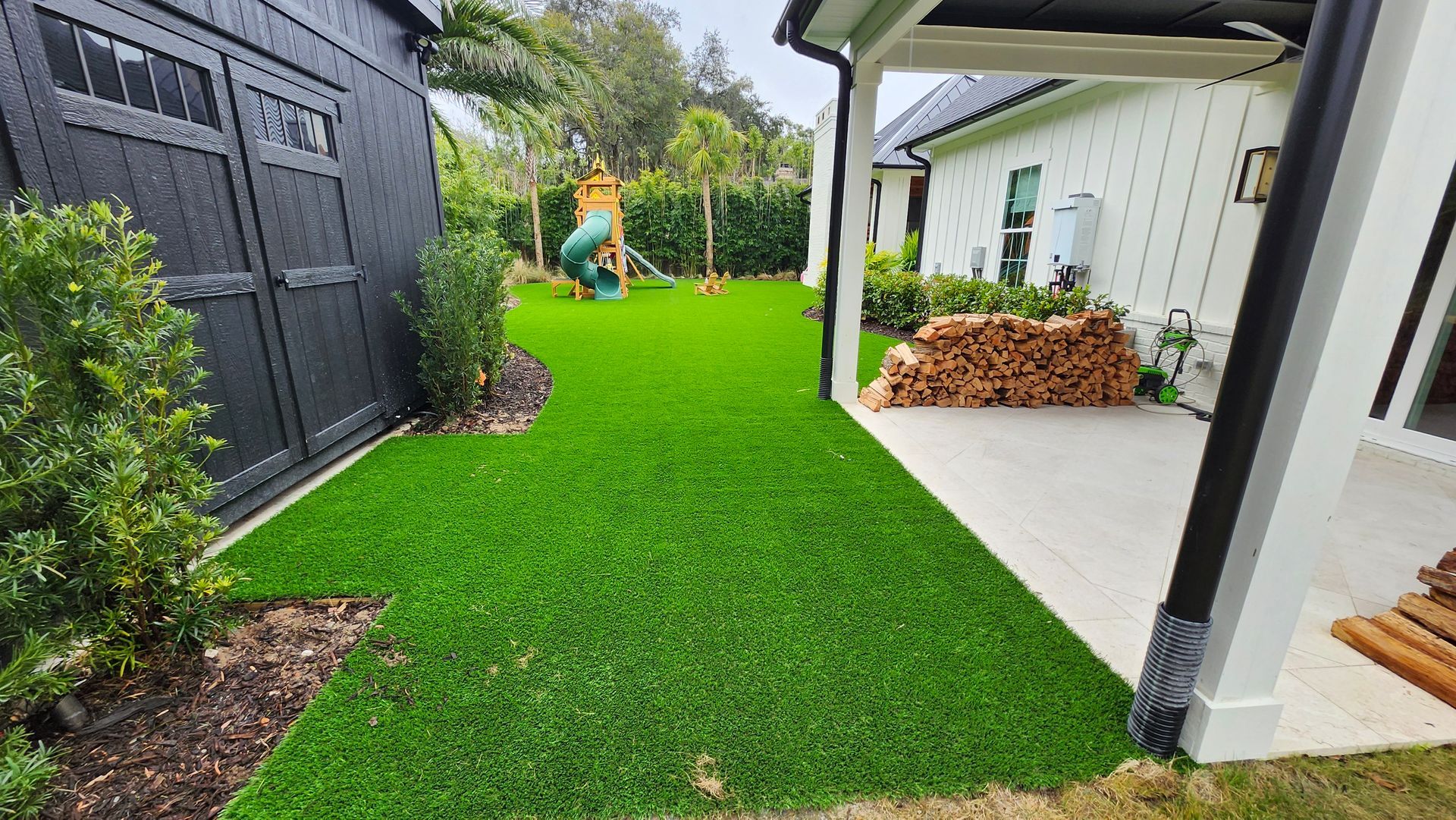 A backyard with a lush green lawn and a playground in the background.
