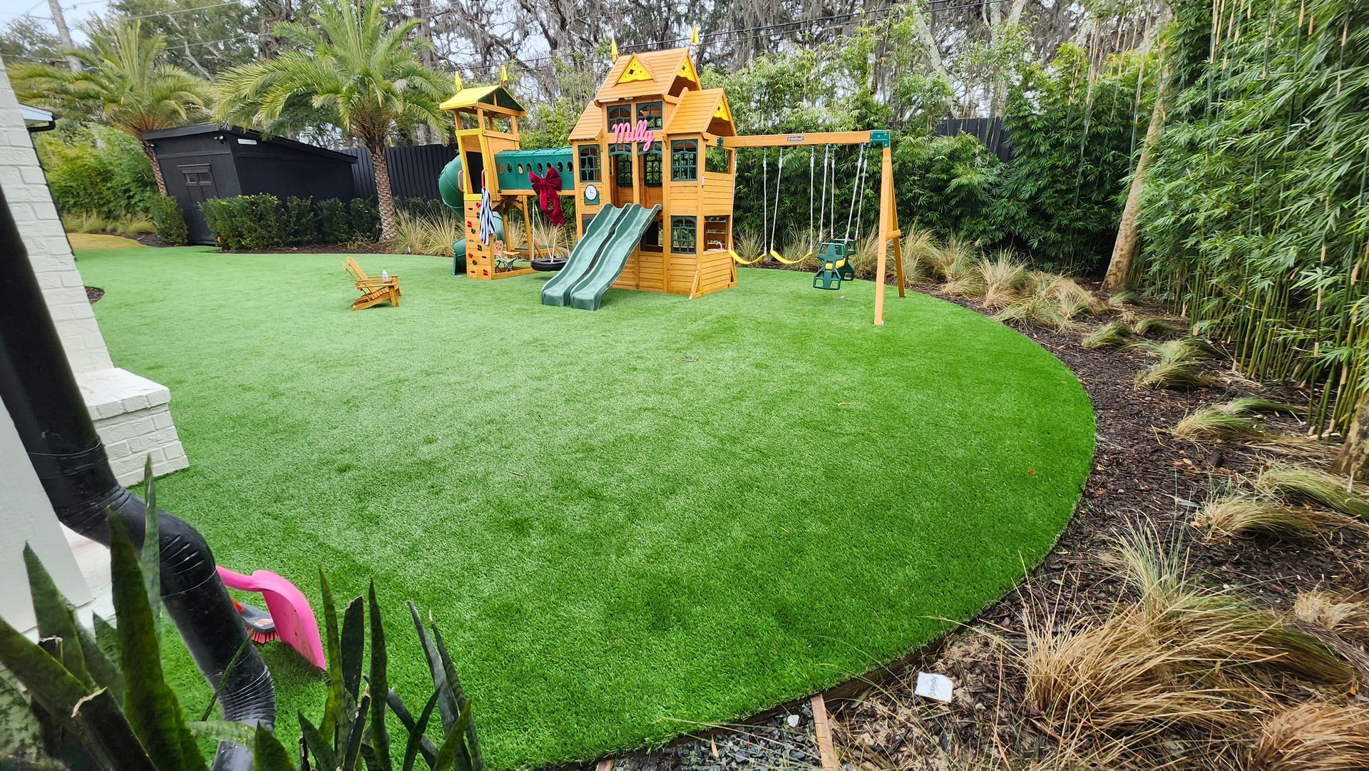 A backyard with a playground and a lush green lawn.
