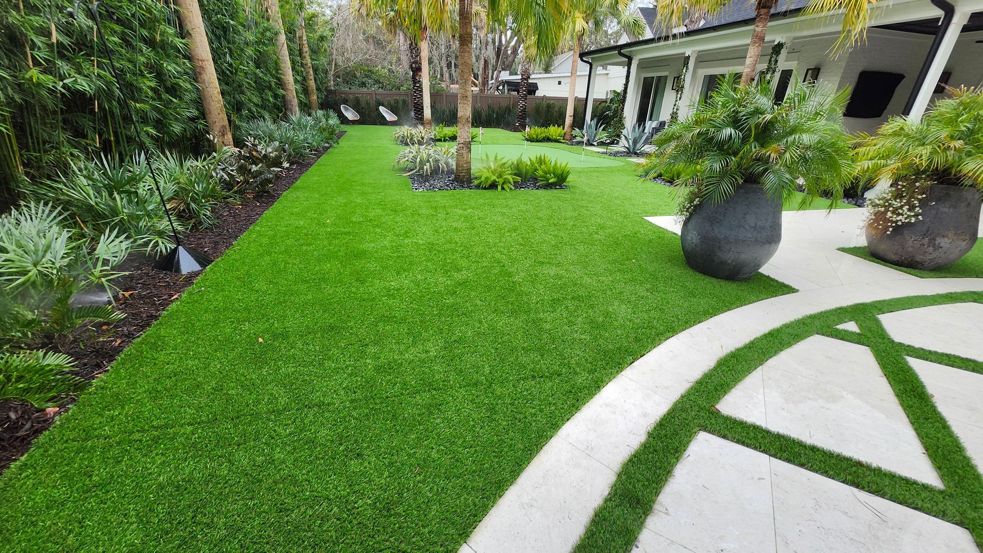 A lush green lawn with a circular walkway leading to a house.