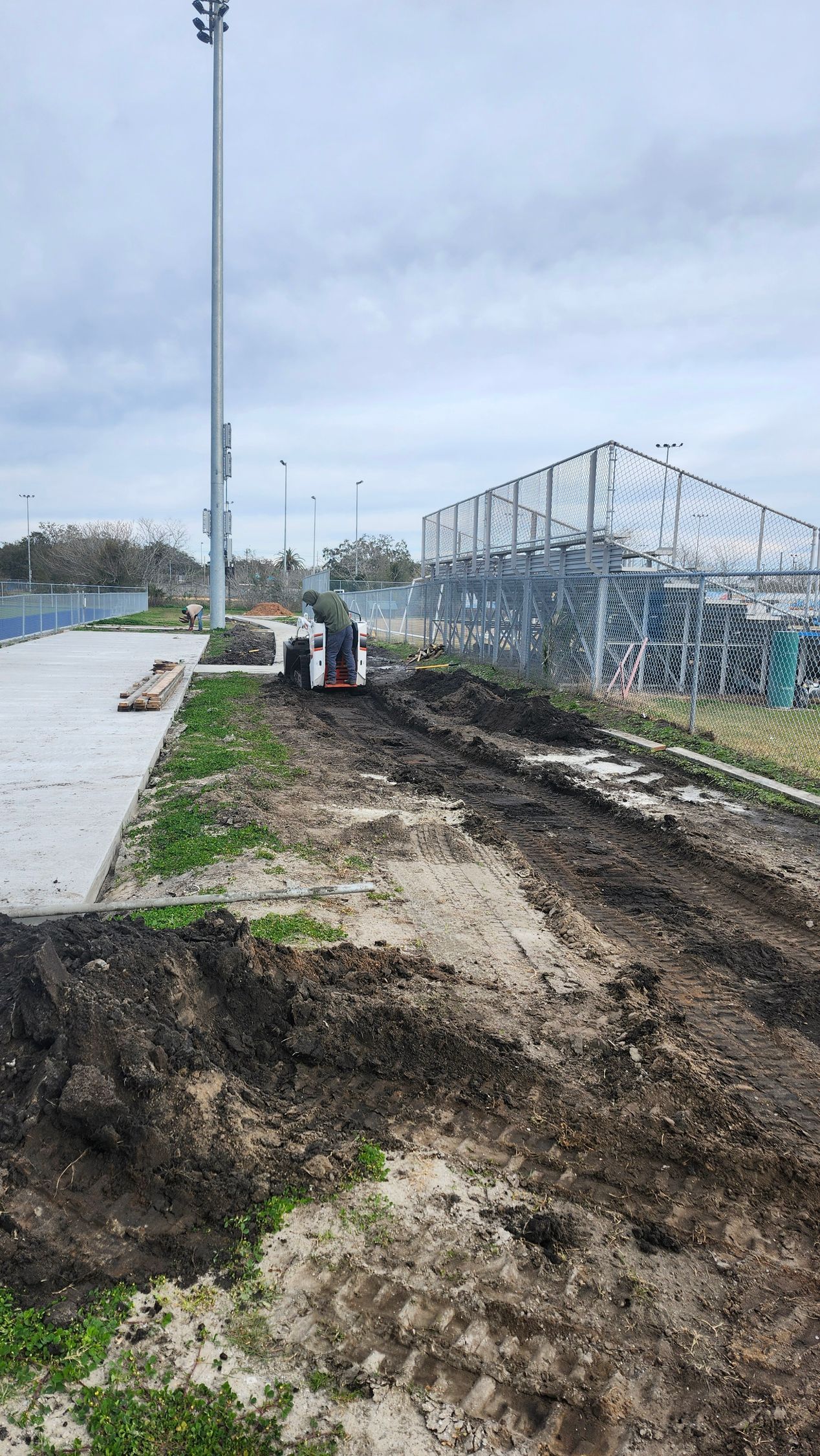 A construction site with a lot of dirt and a fence in the background.