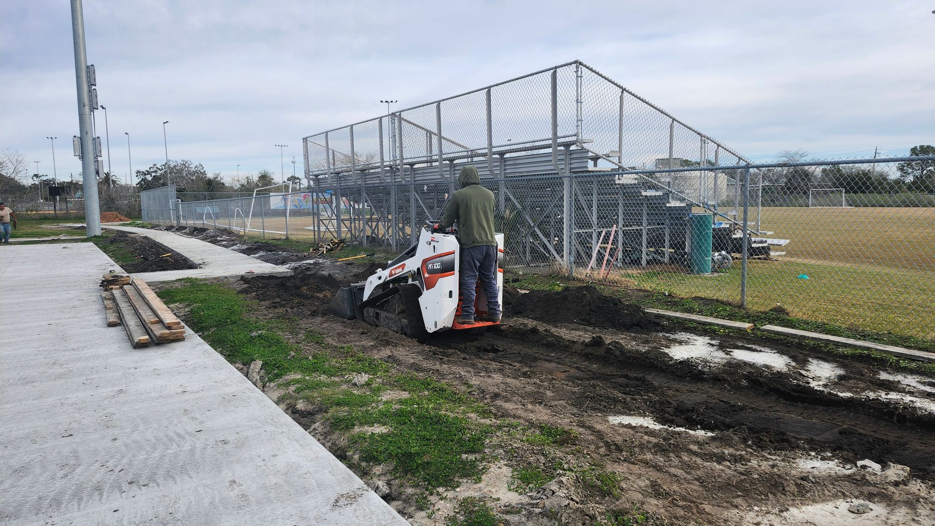 A construction site with a lot of dirt and a fence in the background.