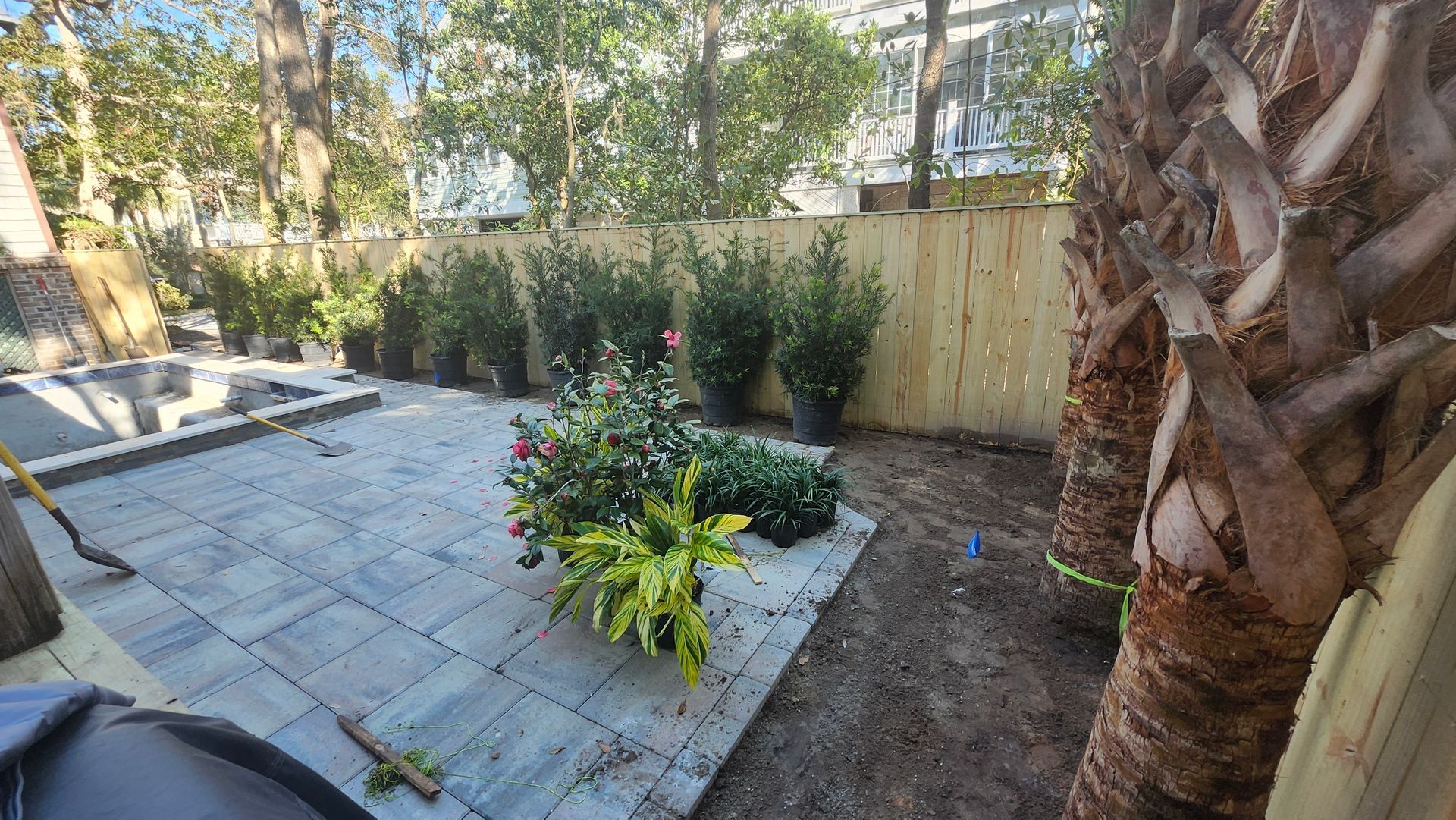 A backyard with a wooden fence and lots of potted plants.