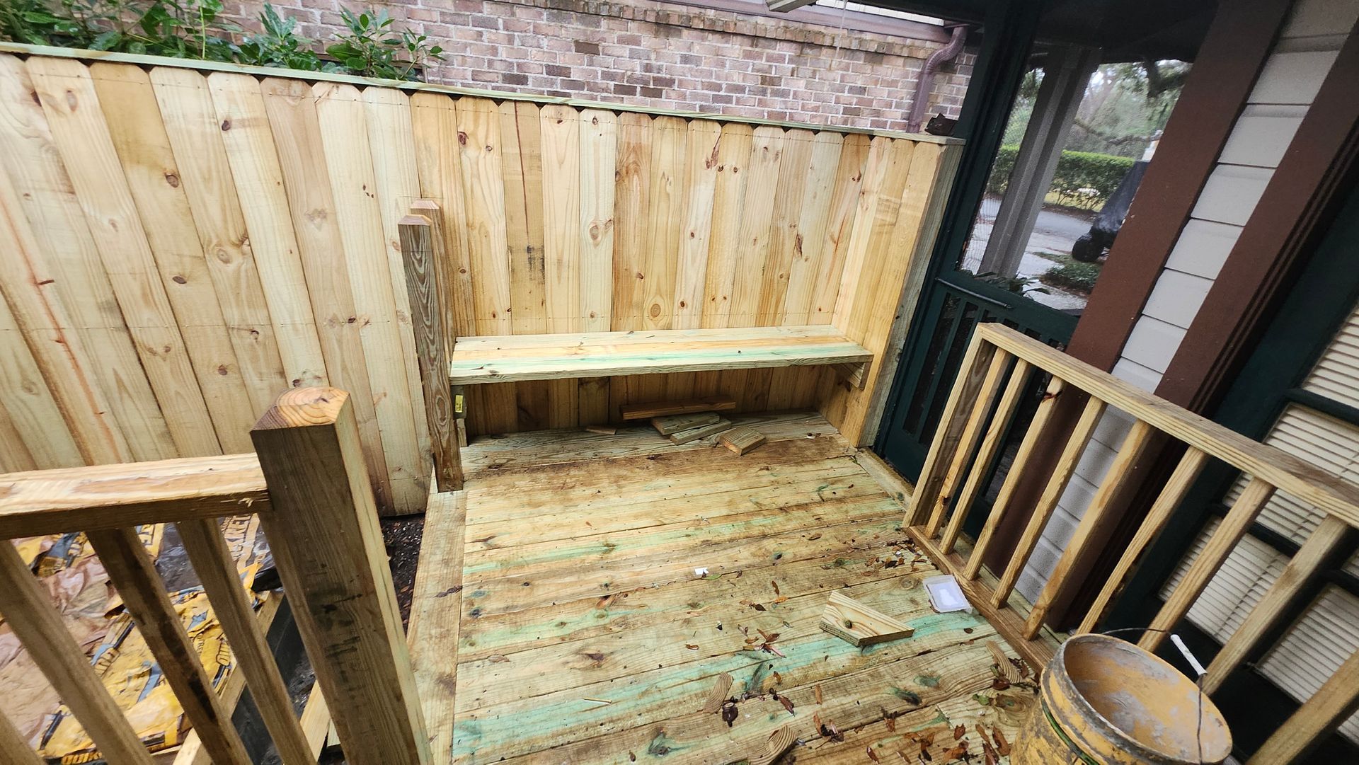 A wooden deck with a bench and a bucket on it.