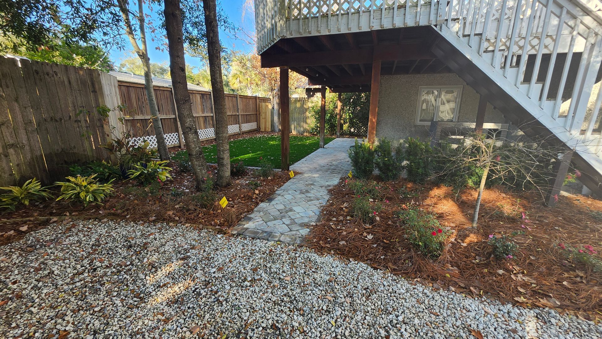 A gravel path leading to a house with stairs leading up to it.