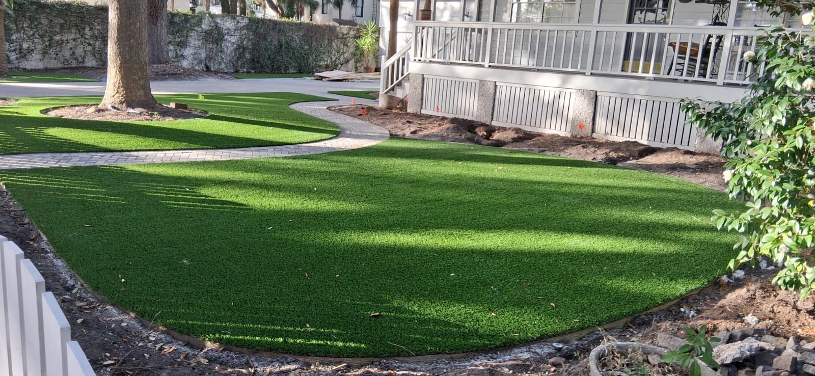 A lush green lawn in front of a house with a walkway.