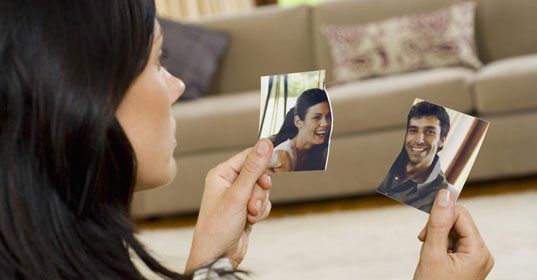 Woman holding a torn photo of her and husband