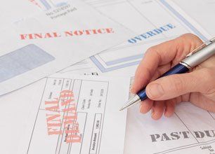 Hand holding a pen over a table of final notice documents