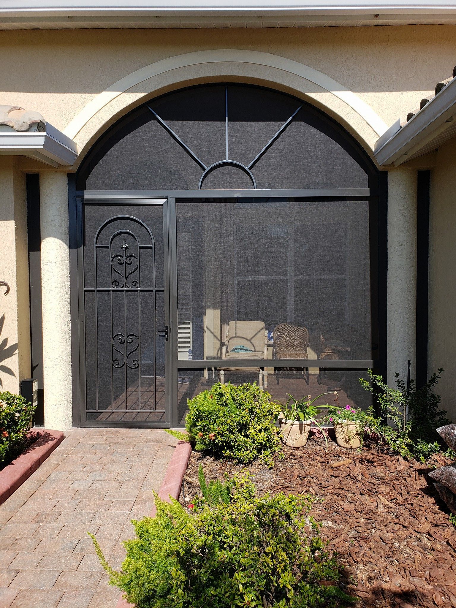 Black security door and screen over a rounded window entrance.