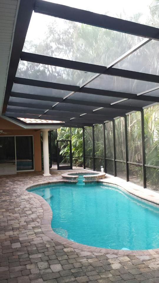 Pool area with turquoise water, screened enclosure, and brick patio.