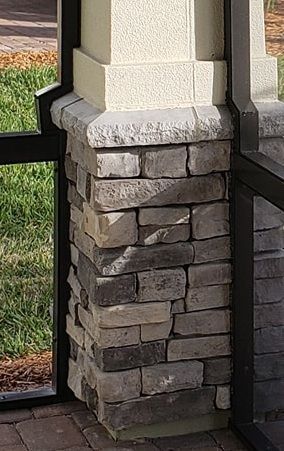 Stone column with dark metal frame, gray and beige bricks.