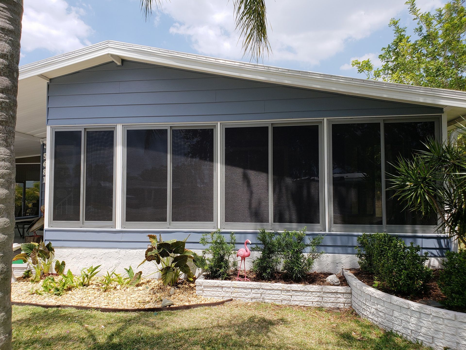 Blue house with screened-in porch, white trim, and landscaping.