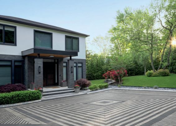 A large white house with a brick driveway in front of it.