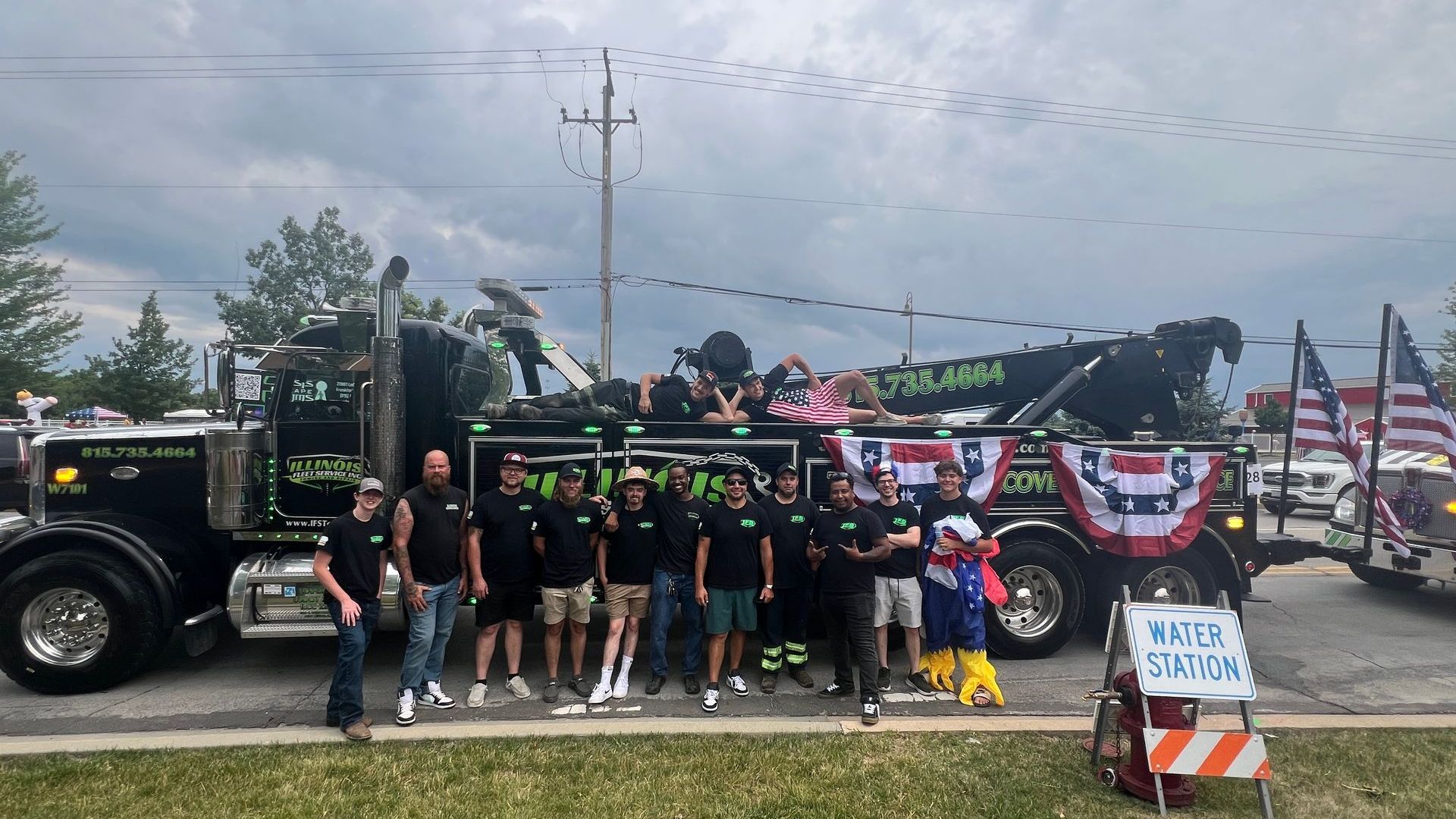 A group of people standing in front of a tow truck.