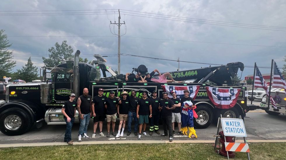 A group of people standing in front of a tow truck.