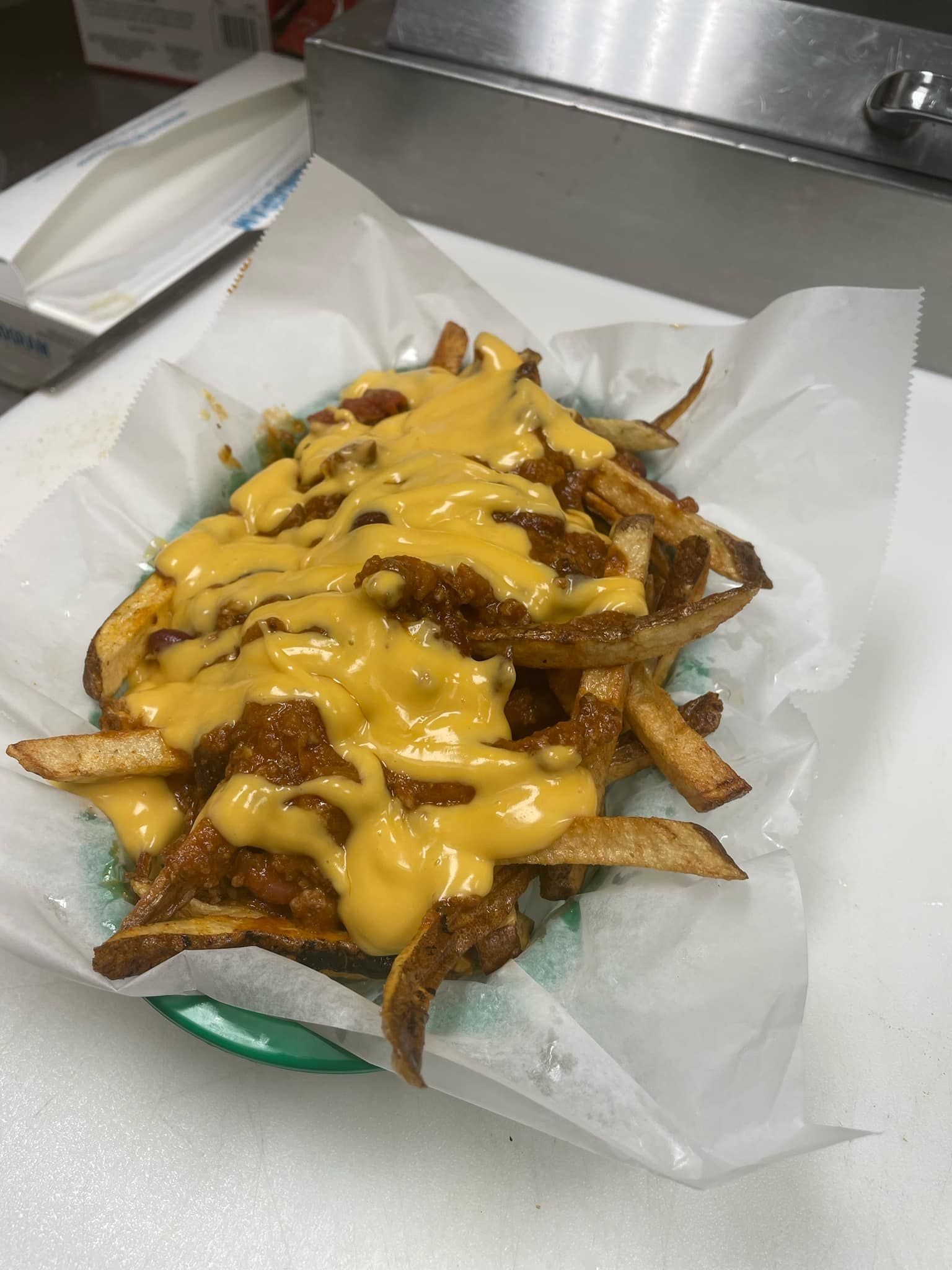 A basket of french fries covered in cheese on a table.