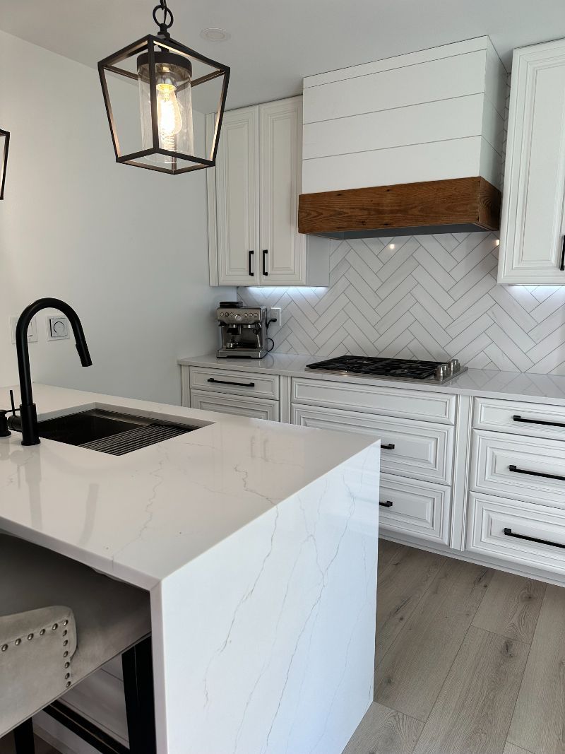 A kitchen with white cabinets, a stove, a sink, and a lantern hanging from the ceiling.