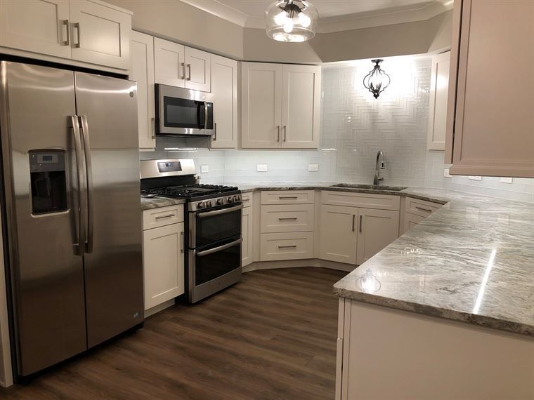 A kitchen with stainless steel appliances and white cabinets.