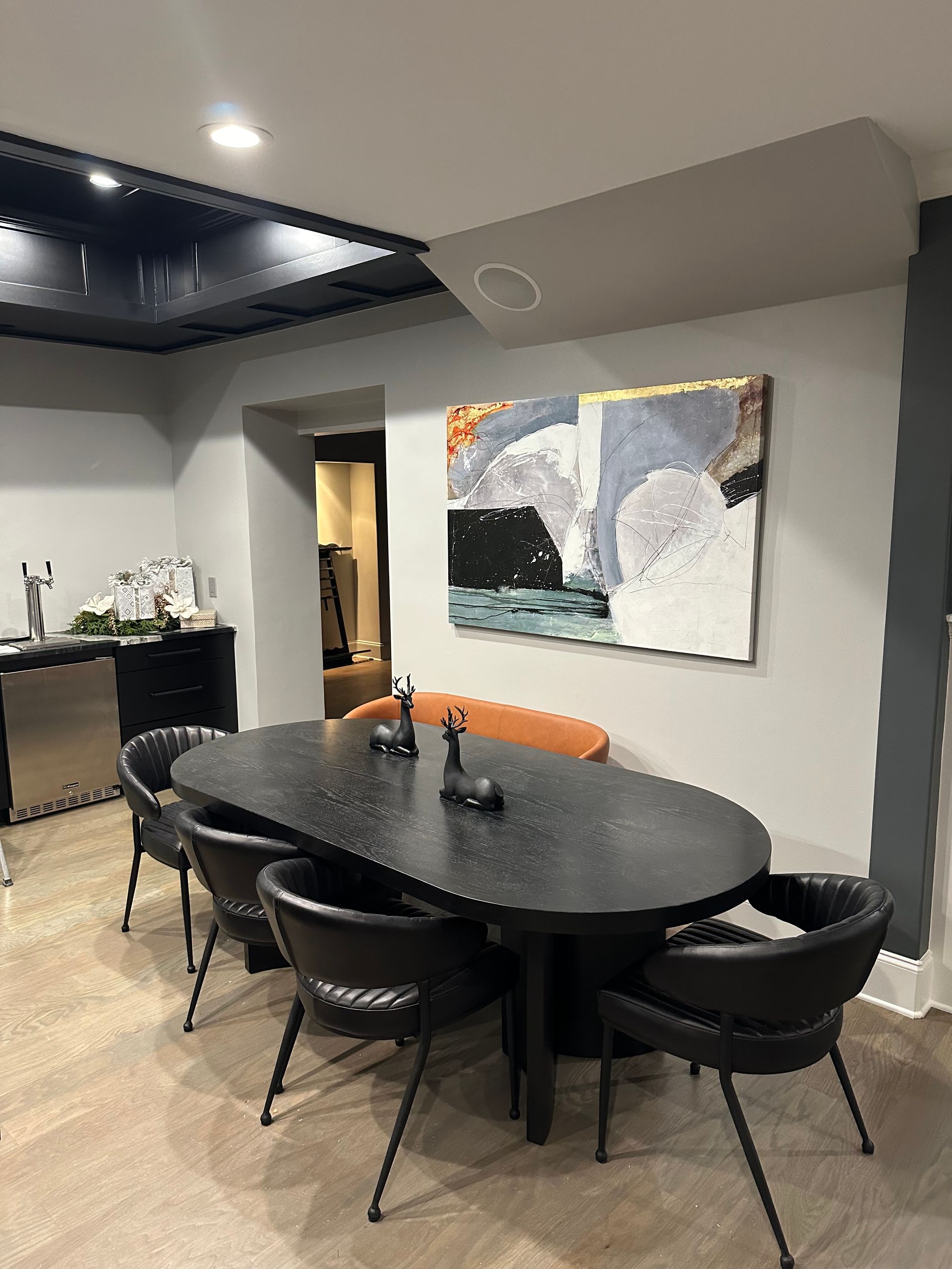 A dining room with a table and chairs and a painting on the wall