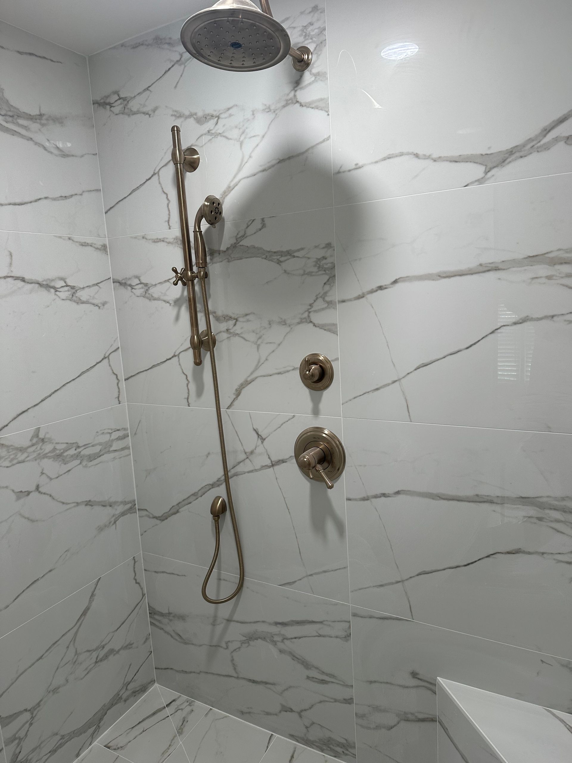 A shower stall with marble tiles and a shower head.