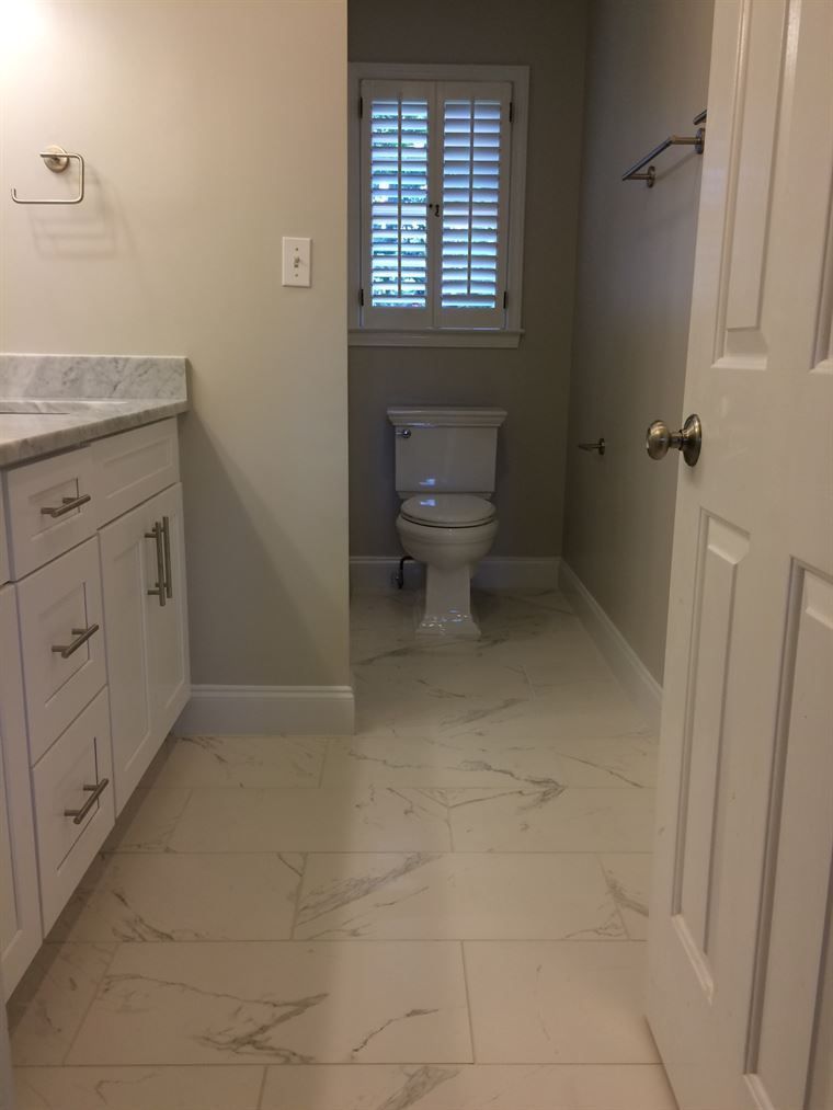 A bathroom with a toilet, sink, and window.