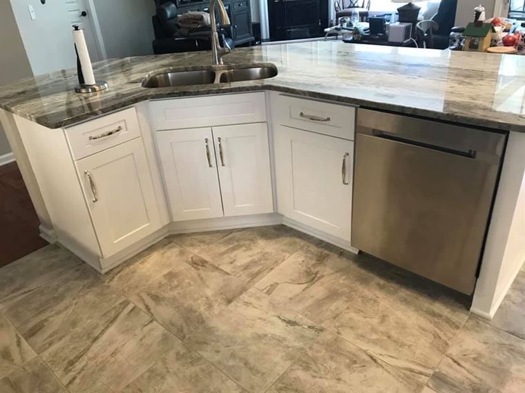 A kitchen with white cabinets, granite counter tops, and a stainless steel dishwasher.