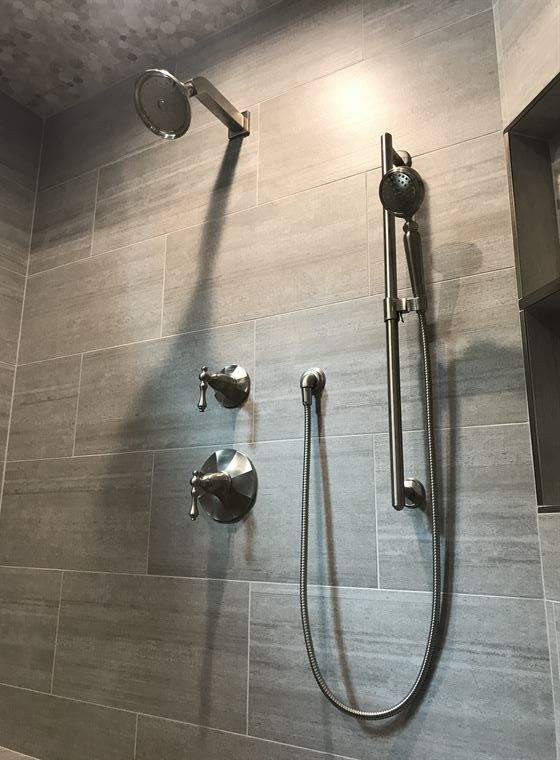 A close up of a shower head and hose in a bathroom.