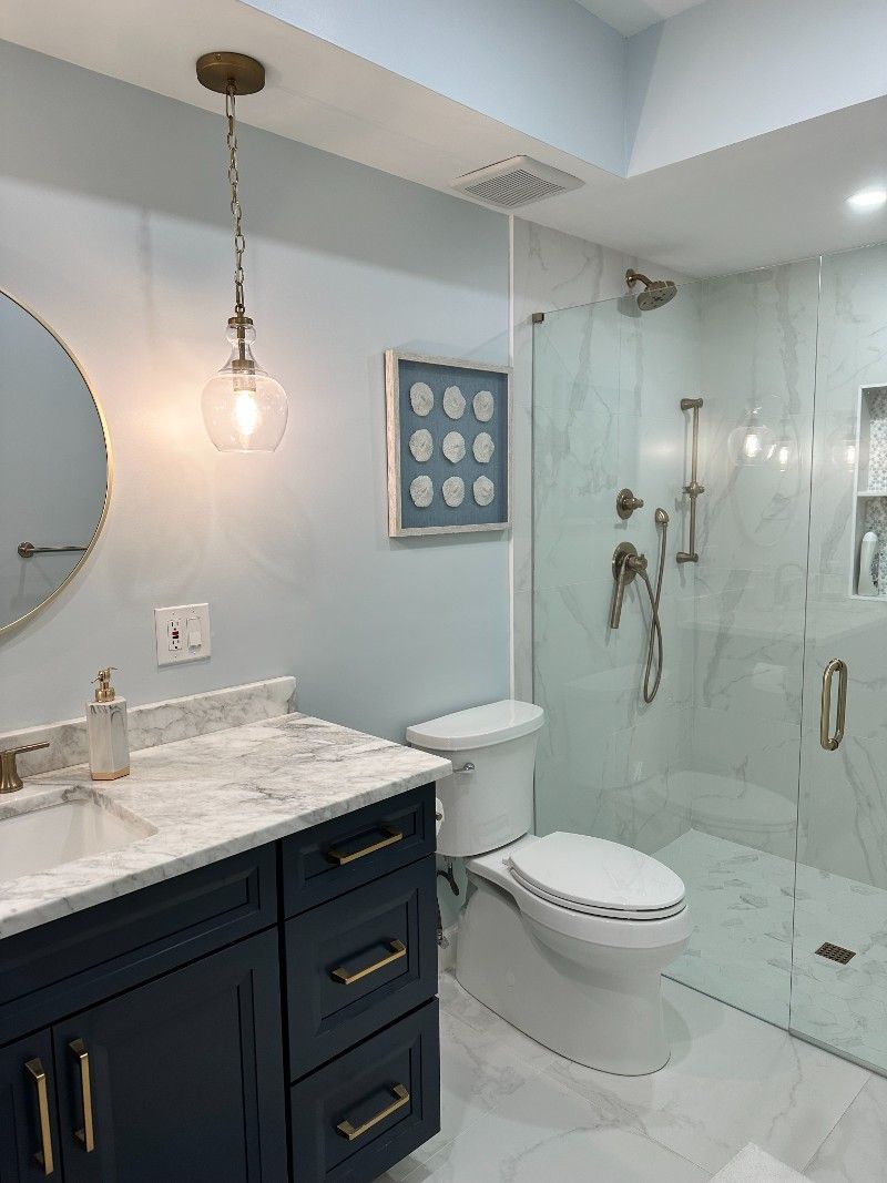 A bathroom with a toilet, sink, mirror and walk-in shower.