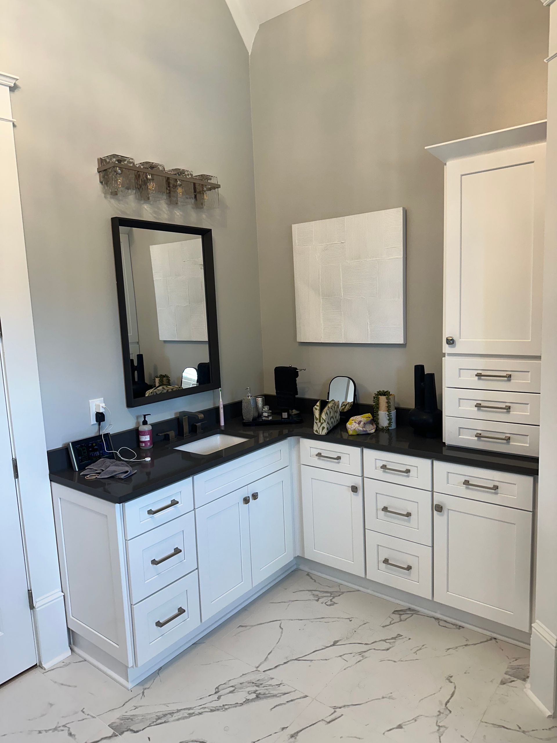 A bathroom with white cabinets, a sink, and a mirror.