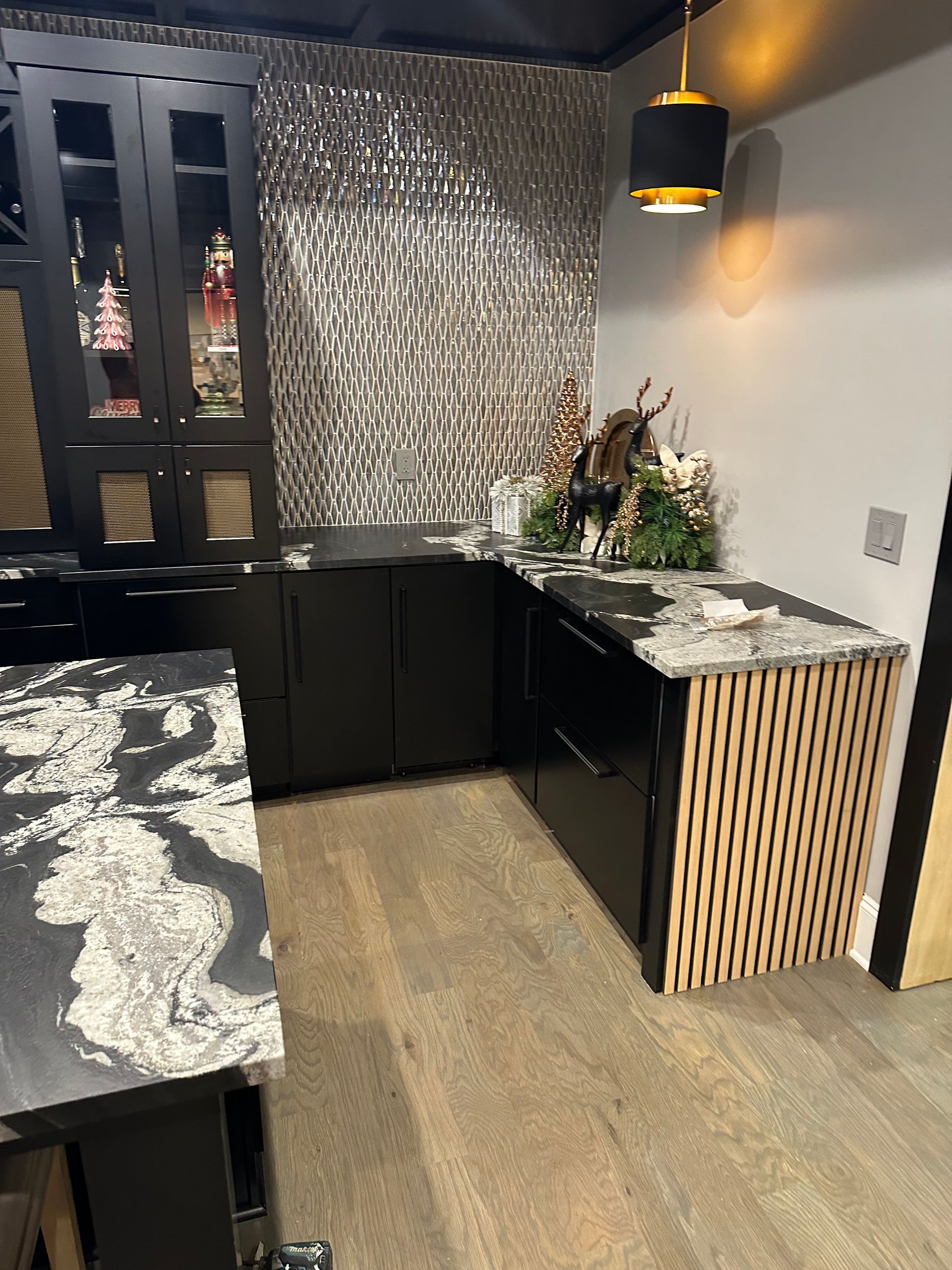 A kitchen with black cabinets and a marble counter top.