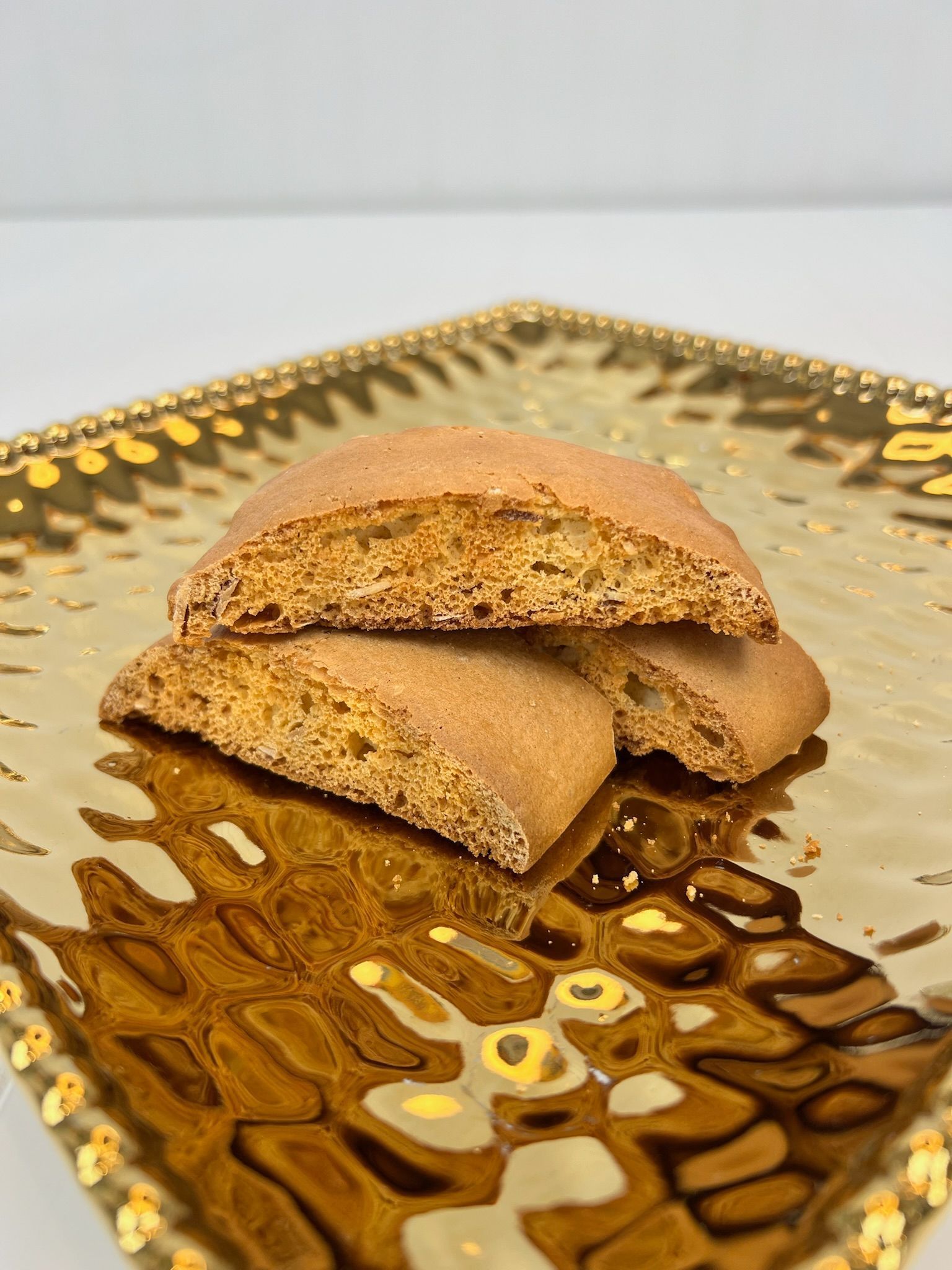 Cookies on a gold, textured plate. Three tan cookies stacked, close-up.