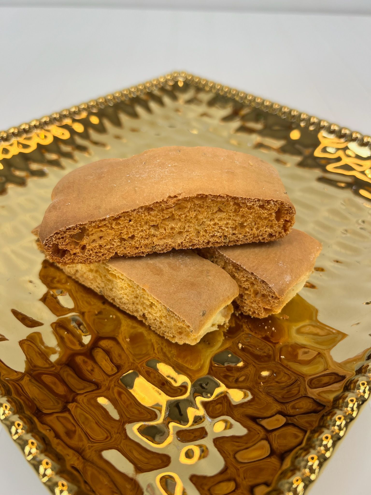 Three light brown cookies on a gold, textured plate.