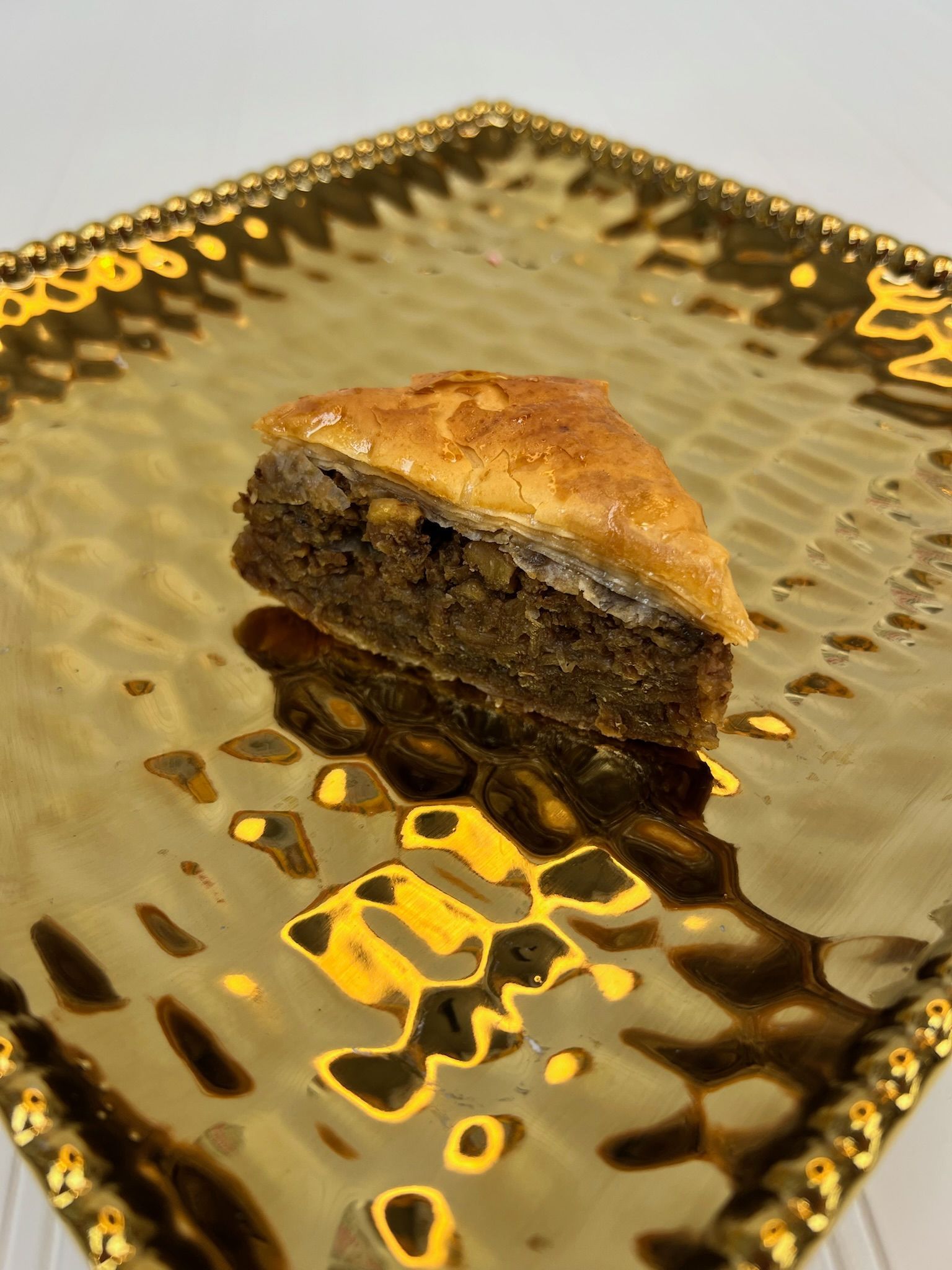 Triangular baklava on a golden, textured plate.