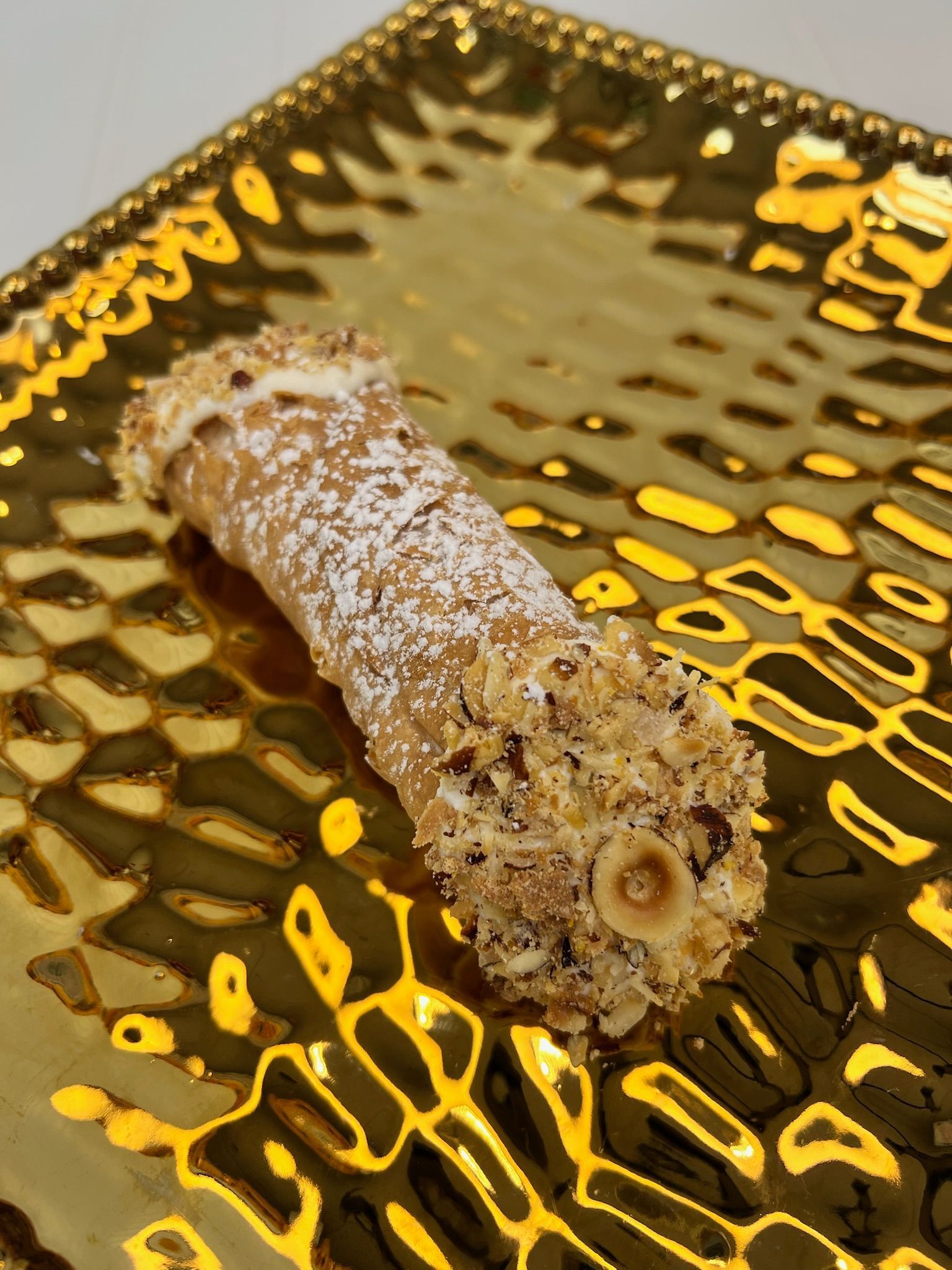 Cannoli pastry on a gold, textured plate.