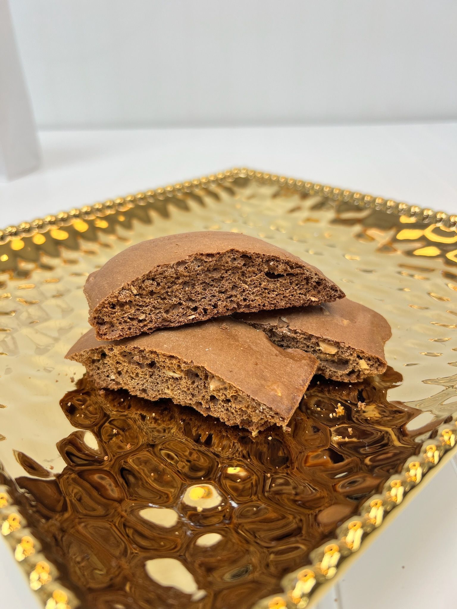 Stack of dark brown biscotti on a gold, square plate.