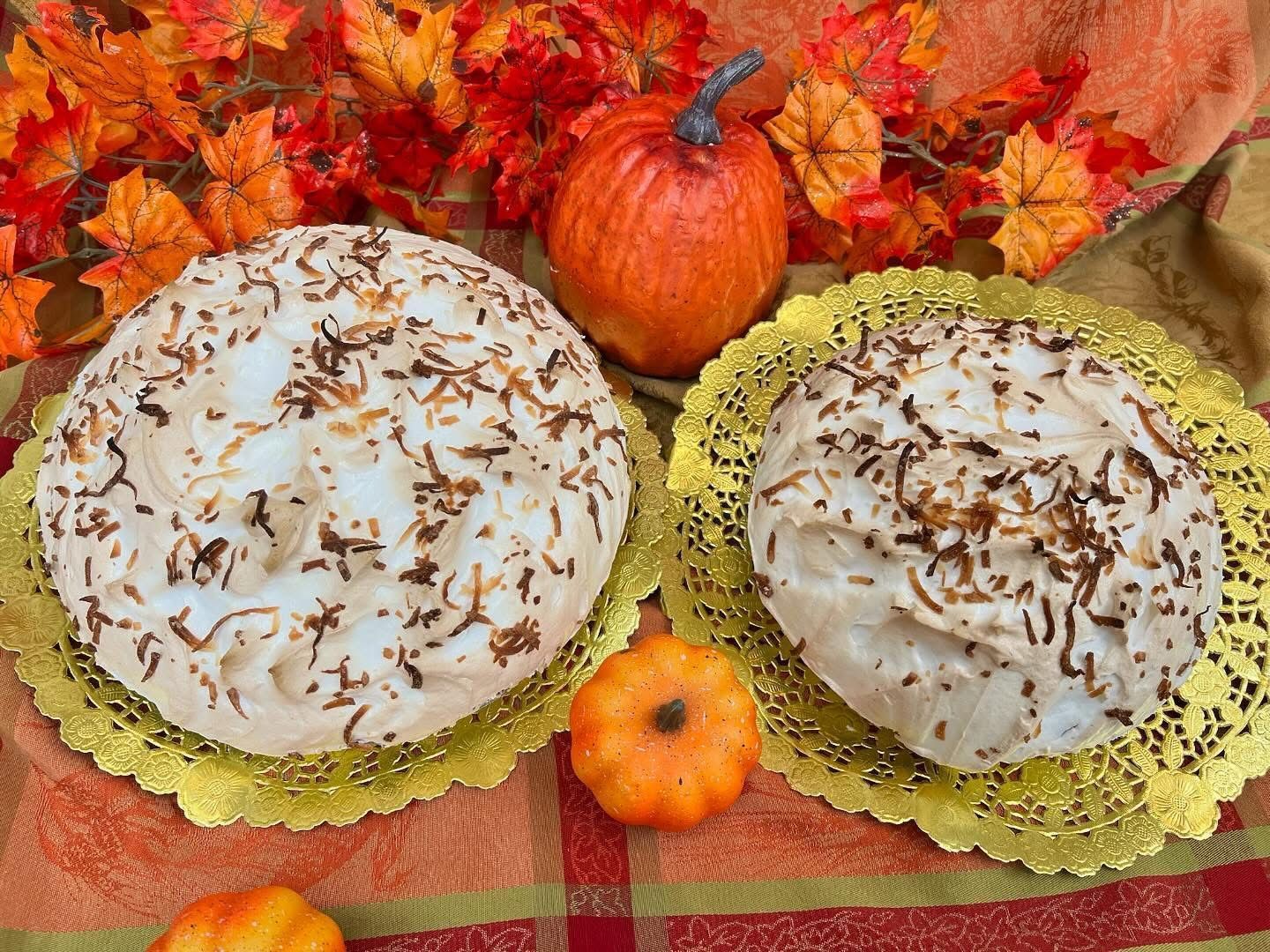 Two coconut meringue pies on gold doilies, surrounded by pumpkins and fall leaves.