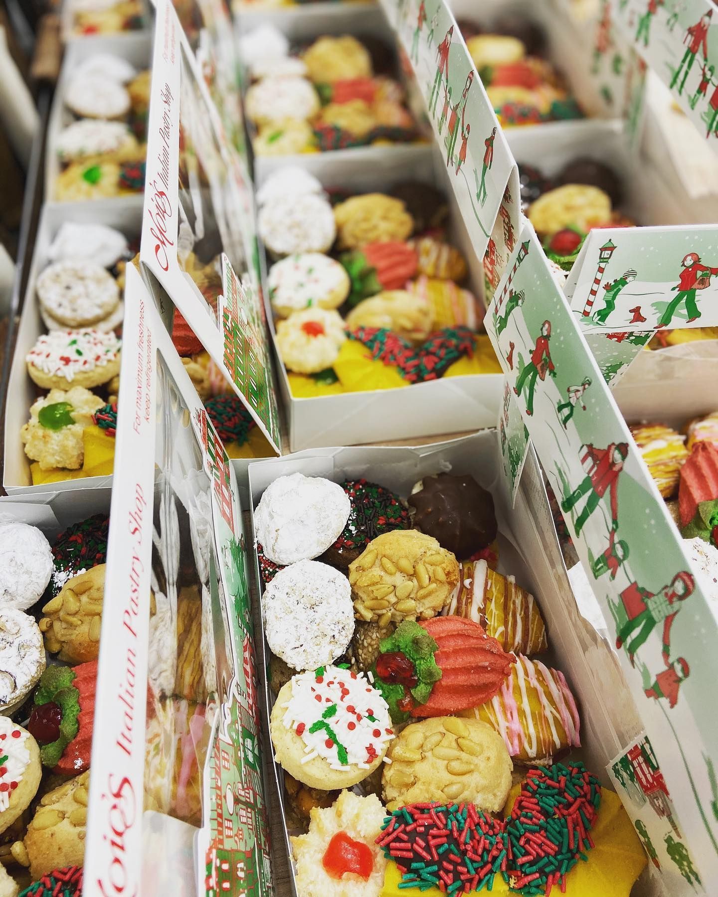 Boxes of assorted colorful Italian cookies, some with holiday decorations.