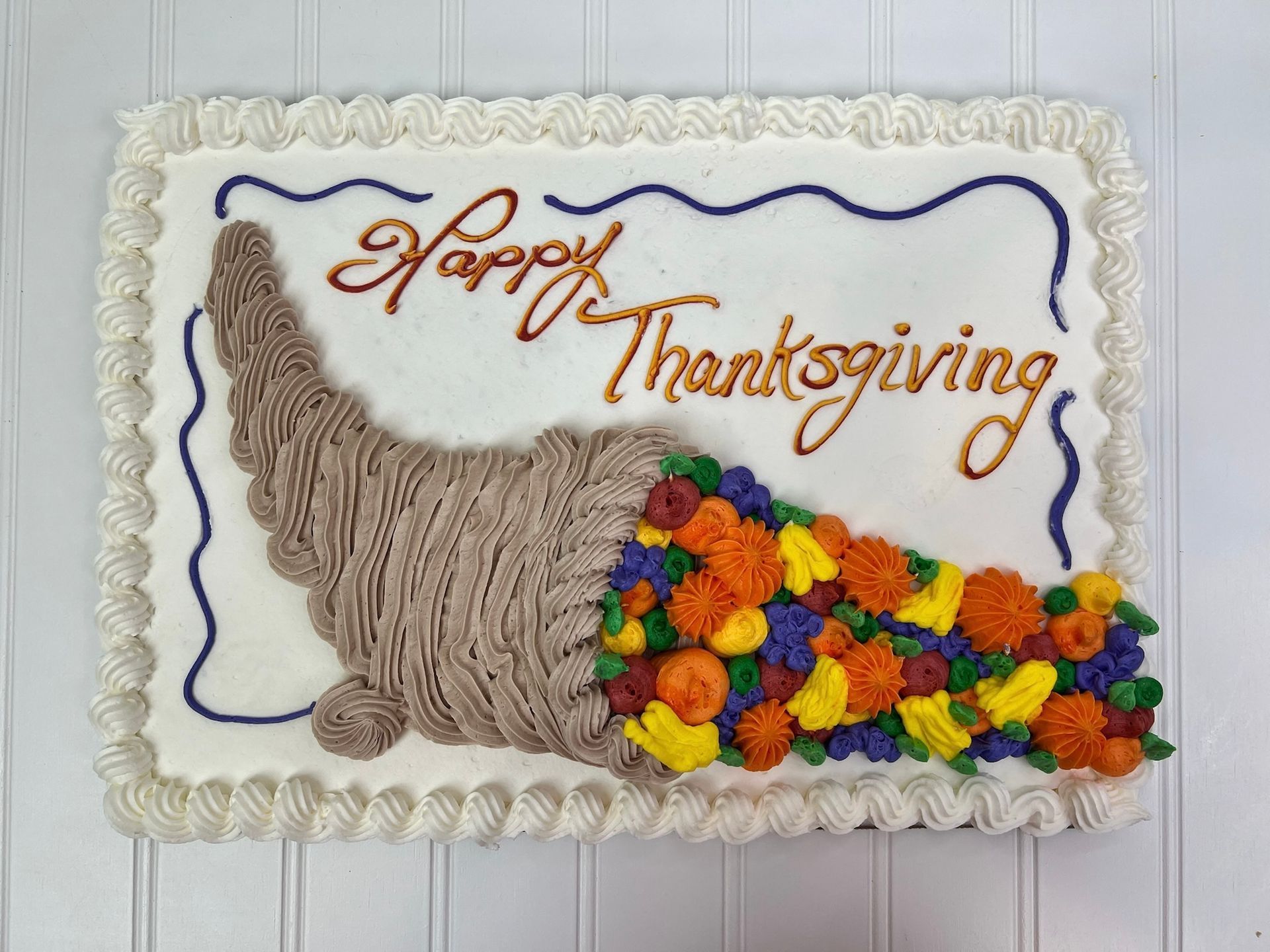Thanksgiving cake decorated with a brown horn of plenty spilling colorful frosting fruits